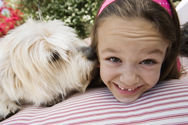young smiling girl's face on cushion with dog nose up against her cheek