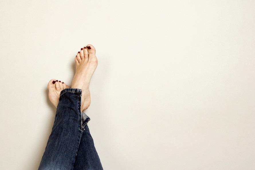 denim jeans with crossed bare feet with red nail polish